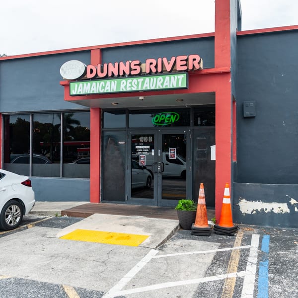 Exterior of Dunns River Jamaican Restaurant, with a red and gray facade, and an "OPEN" sign.