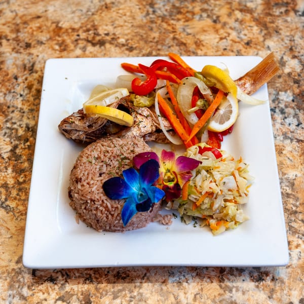 Dunns River Island Cafe's whole fried fish with rice, vegetables, and colorful orchid garnishes.