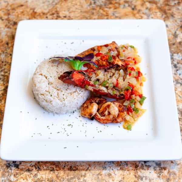 Dunns River Island Cafe's Jamaican dish with lobster, shrimp, rice, and colorful salsa on a white plate.