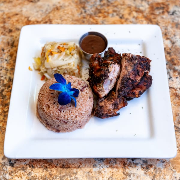 Dunns River Island Cafe's jerk chicken with rice and peas, steamed cabbage, and dipping sauce.