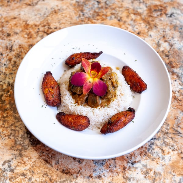 Dunns River Island Cafe's Jamaican curry goat with rice, plantains, and an orchid garnish.