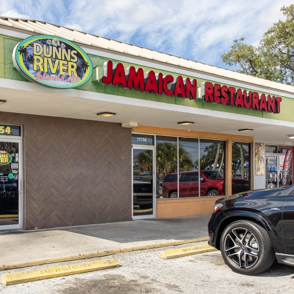 Exterior of Dunns River Jamaican Restaurant with a black car parked in front.